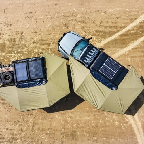 Overhead view of 4WDs with two Bush Company awnings extended, outdoor gear, and a solar panel parked on sandy terrain.