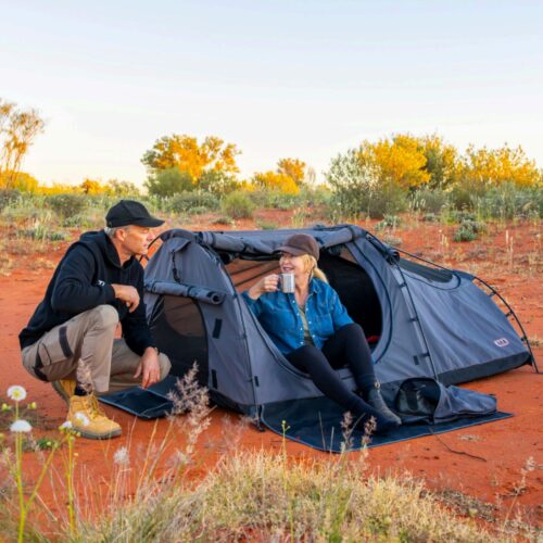 Man and women sit in ARB Skydome 3 Double Swag in dessert drinking coffee